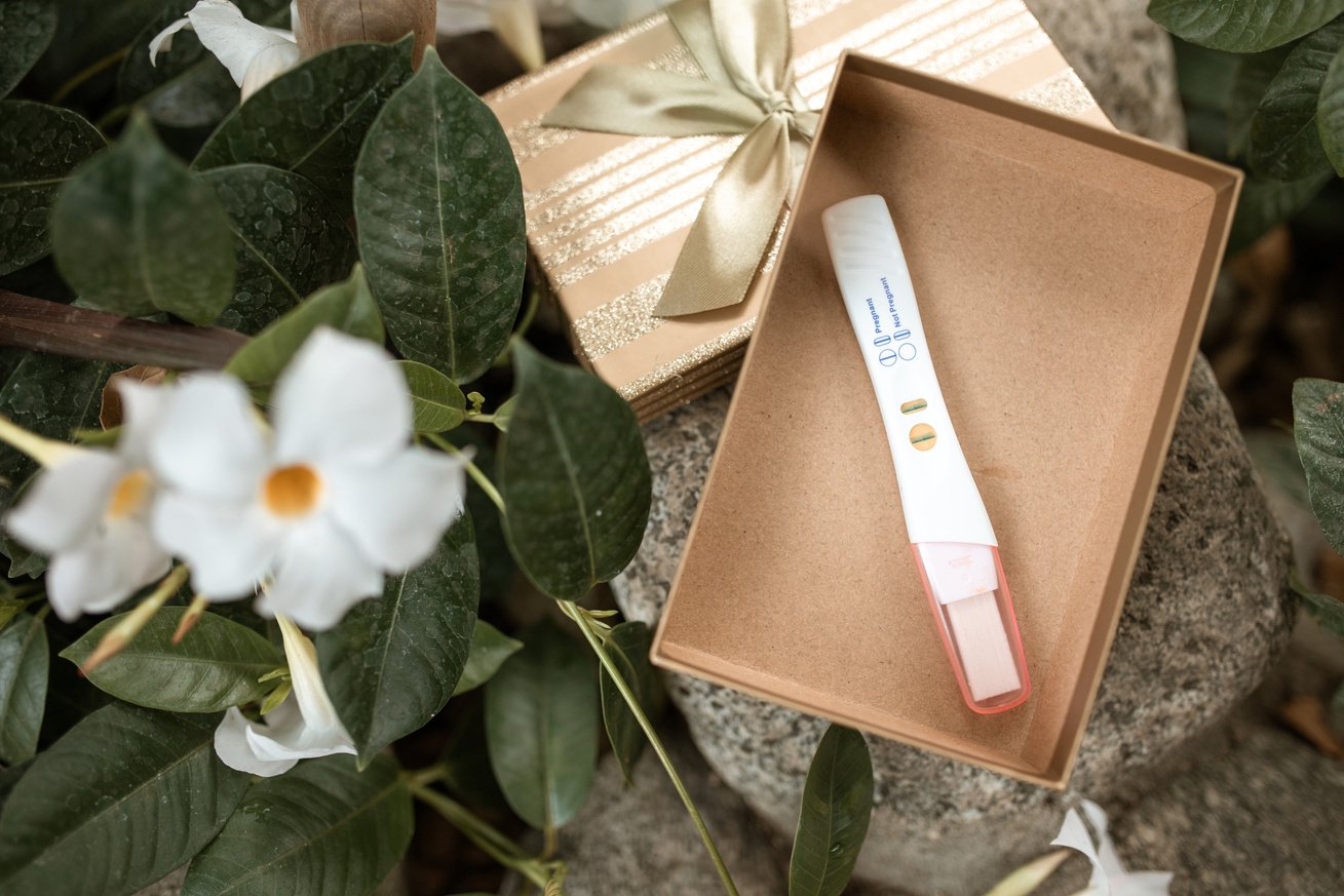 White Flower Beside Brown Box With Pregnancy Test 